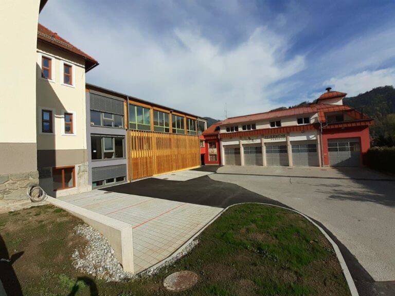 Parkplatz mit modernen Schulgebäuden im Hintergrund.