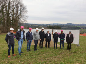 Vertreter beim Spatenstich der Siedlung Bartholomä stehen vor dem Baustellenschild auf dem Grundstück in St. Bartholomä.
