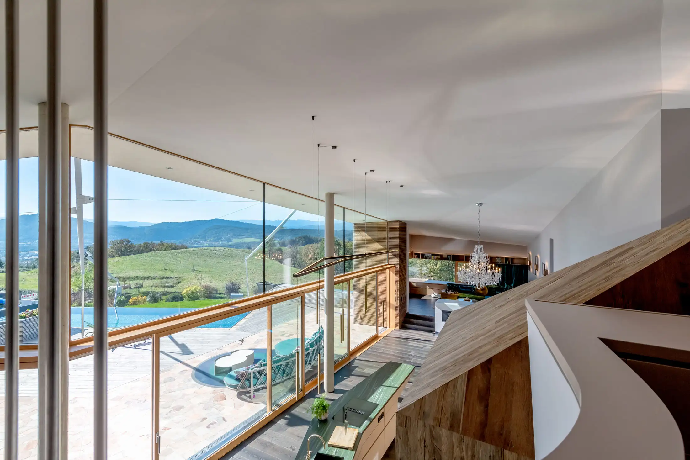 Lichtdurchflutetes Wohnzimmer mit Panoramaverglasung und Blick über die Hügel der Steiermark – modernes Einfamilienhaus von Hoppaus & Hasslinger