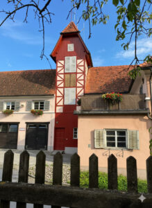 Sanierter Schlauchturm Feuerwehrhaus Frohnleiten mit roter Holzfassade, Fachwerk-Elementen und weißen Fensterläden