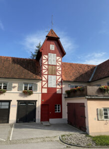 Sanierter Schlauchturm und Feuerwehrhaus Frohnleiten bei Tageslicht, rote Holzfassade mit weißen Fensterläden