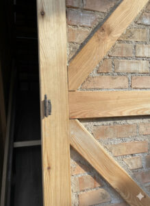 Innenansicht der neuen Holzkonstruktion im Schlauchturm, senkrechter Rahmen und schräge Streben vor Ziegelwand