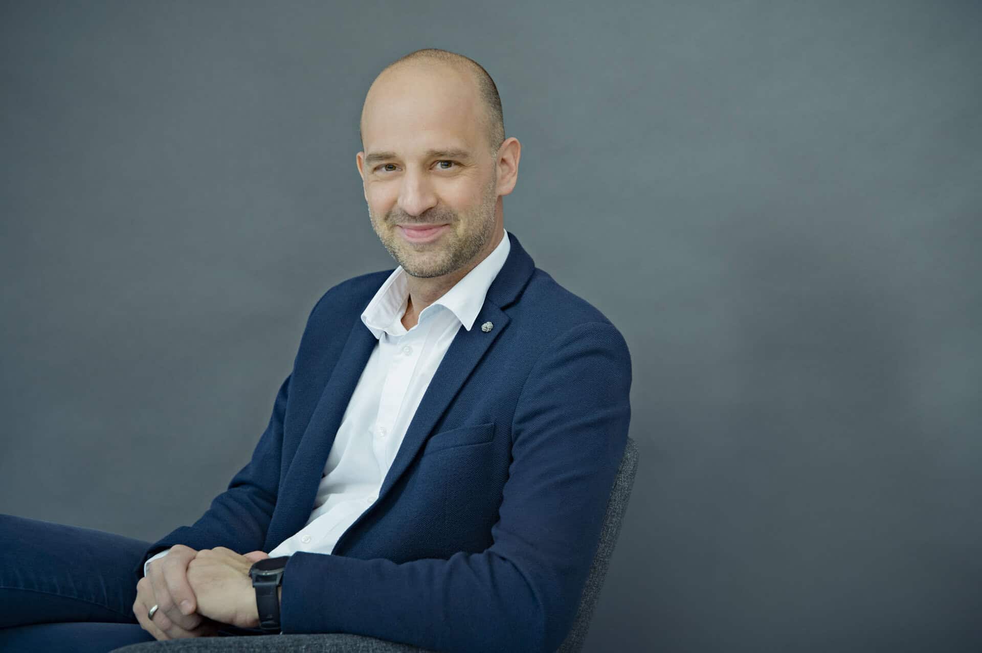 Stefan Glössl, Geschäftsführer, im blauen Sakko sitzend im Studio