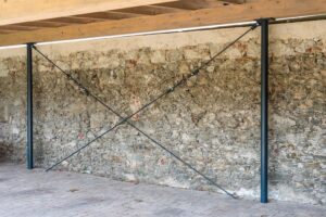 Kreuzverstrebung an Natursteinwand unter dem Carportdach