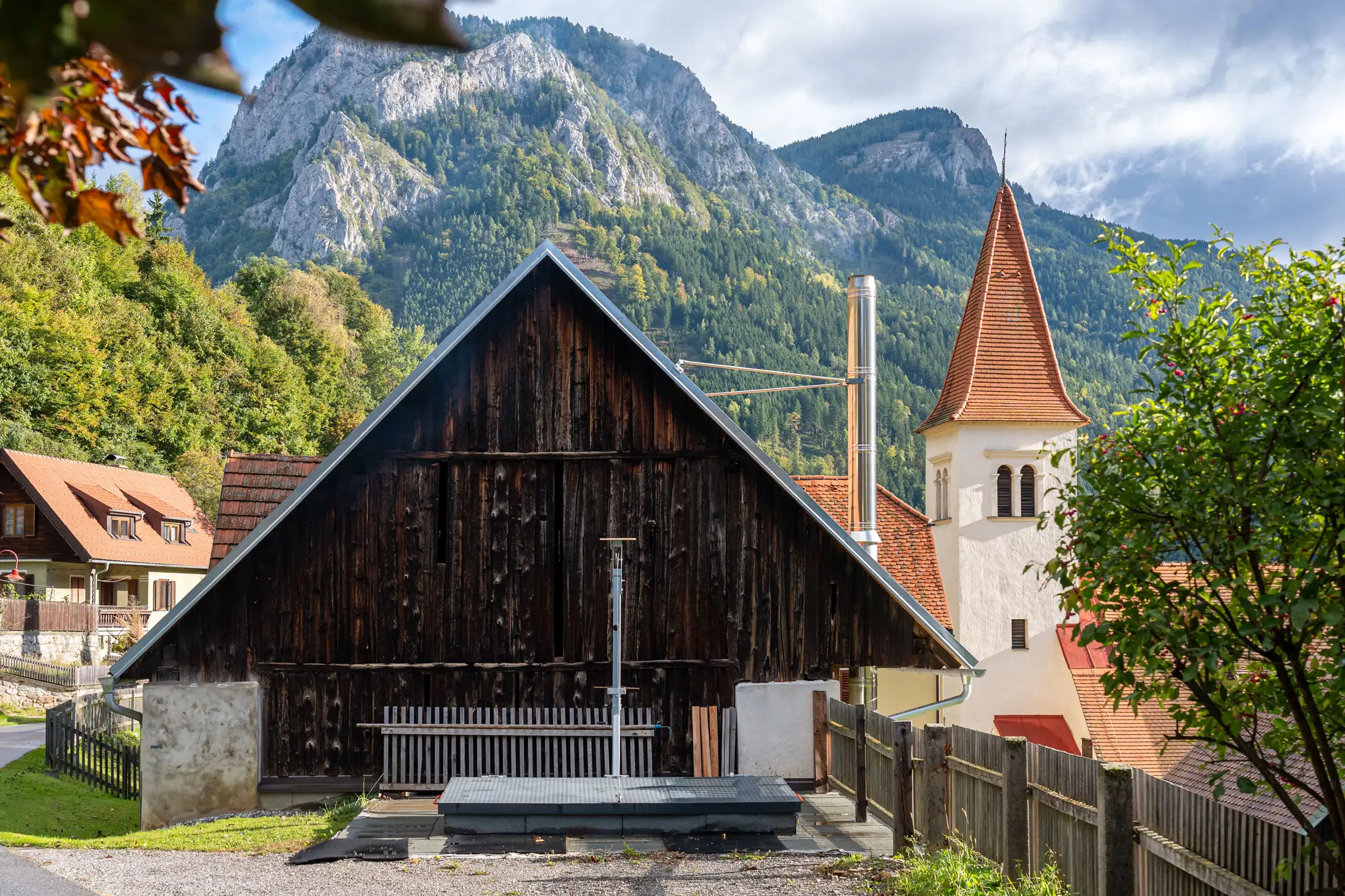 Historische Dorfansicht mit altem Holzstadel, Kirchturm und Bergkulisse in der Steiermark