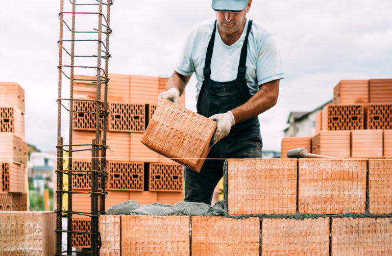 Maurer beim Verlegen von Ziegelsteinen auf einer Baustelle.