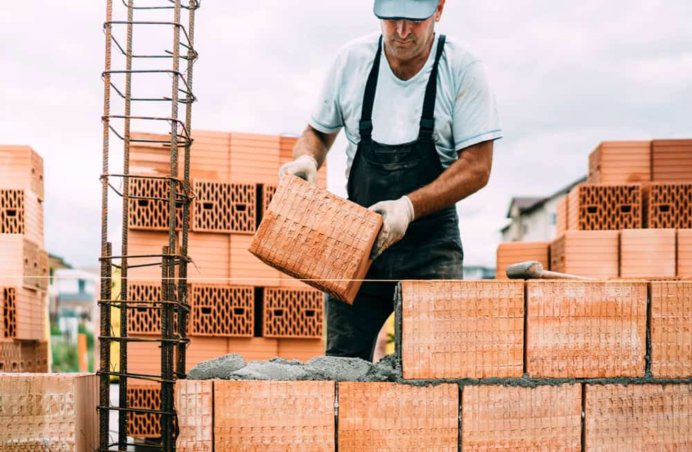 Maurer beim Verlegen von Ziegelsteinen auf einer Baustelle.