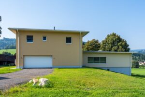 Seitenansicht des Hauses mit Garage und grüner Hanglage