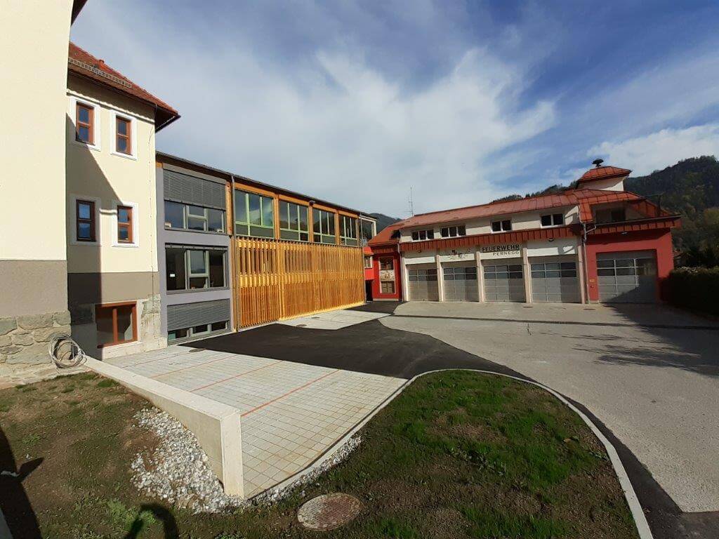 Parkplatz mit modernen Schulgebäuden im Hintergrund.